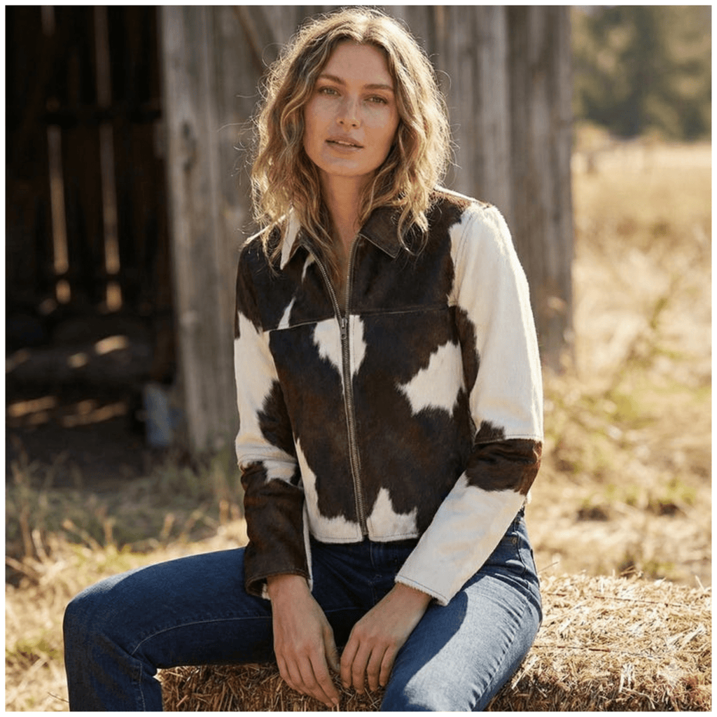 Side view of model wearing women brown & white cowhide leather jacket with zip-up front in genuine leather