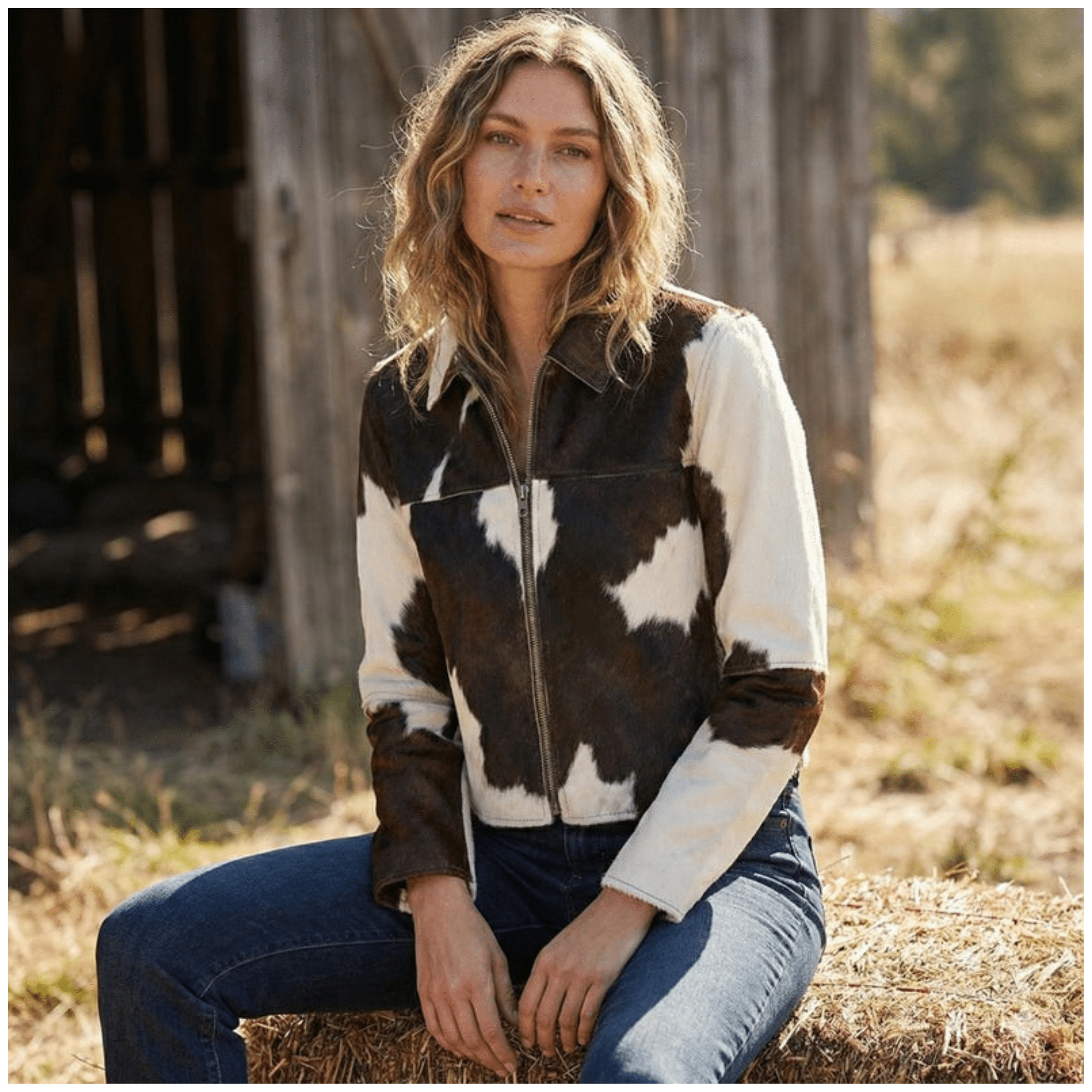Side view of model wearing women brown & white cowhide leather jacket with zip-up front in genuine leather